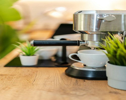 A fresh glass of clean mineral water placed beside a modern espresso coffee maker on a bright kitchen countertop