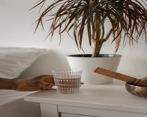 A peaceful home bedroom interior during early evening with soft lighting and a glass of water on a side table